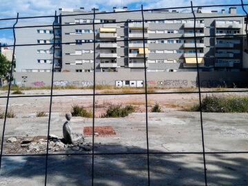 Barcelona Street Photography, building fence, gray beton, stone figure, street art sculpture